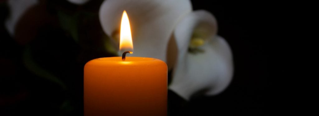Close up of orange candle flame and lily flowers symbolizing hope for the people involved in a motorcycle accident