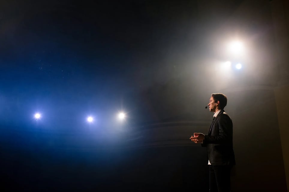 Man Speaking Through A Microphone In Dark Conference Hall-1