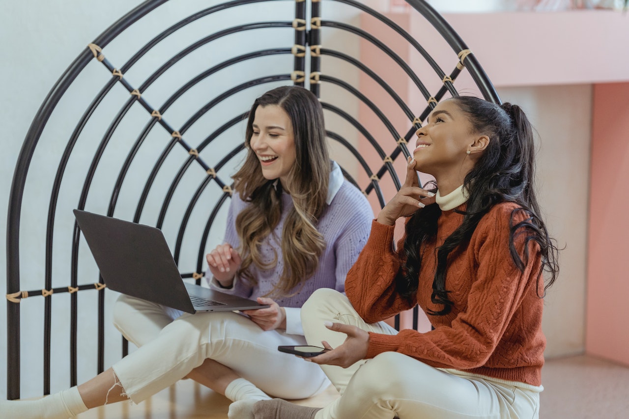 two-women-talking-and-laughing-while-using-laptop-professional-coaching