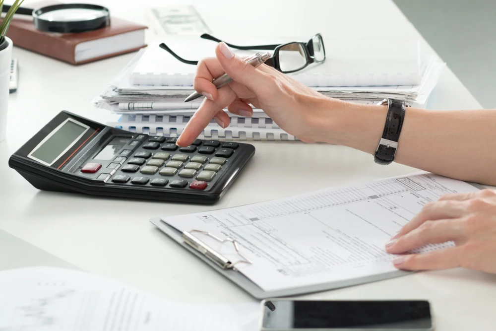 Person with a clipboard and calculator filling out a personal injury claim form